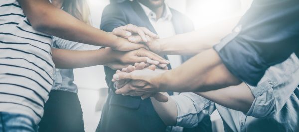 Close up view of young business people putting their hands together. Stack of hands. Unity and teamwork concept.